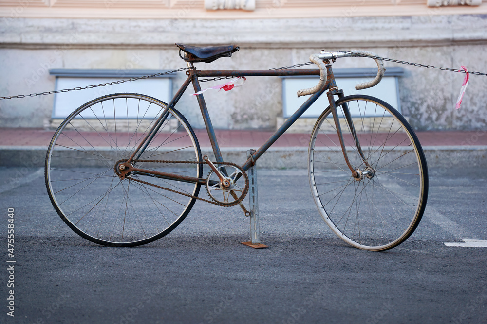 Old broken retro bike on a city street takes up space for a car in a parking lot. Parking space shortage concept