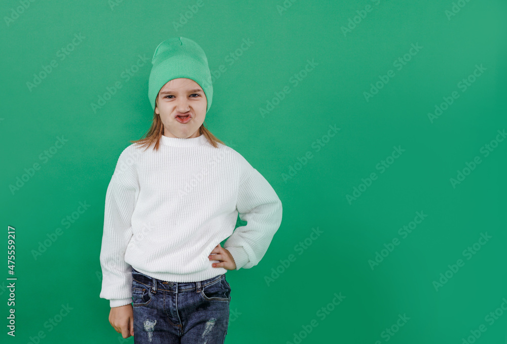 A happy boy is making faces and having fun on the background of a green studio. the kid in bright clothes looks playful, laughs, smiles. A happy boy is making faces and having fun on the background of a green studio. the kid in bright clothes looks playful, laughs, smiles.