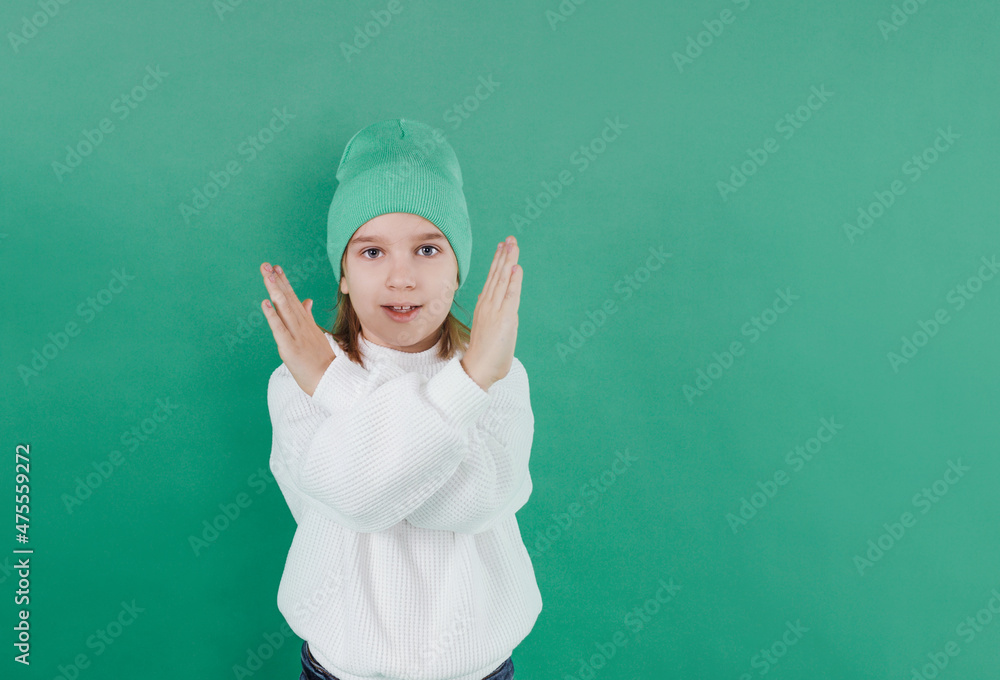 no. a boy in a white sweater and hat stands with his arms crossed in front of him on an isolated green background. no. a boy in a white sweater and hat stands with his arms crossed in front of him on an isolated green background.
