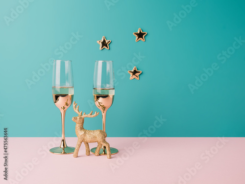 Golden champagne glasses with stars and reindeer on a pastel colorful background. New Year celebration minimal background photo