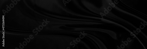 Black gray satin dark fabric texture luxurious shiny that is abstract silk cloth panorama background with patterns soft waves blur beautiful.