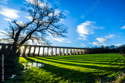 The Ouse Valley Viaduct on an autumn afternoon with clouds streaming overhead and long shadows across the field.