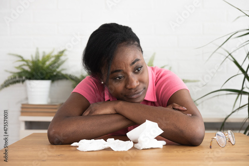 Young beautiful black African American woman sitting at home is sad and depressed because of an argument and breaking up with her boyfriend. Crying desperate hopeless female student.