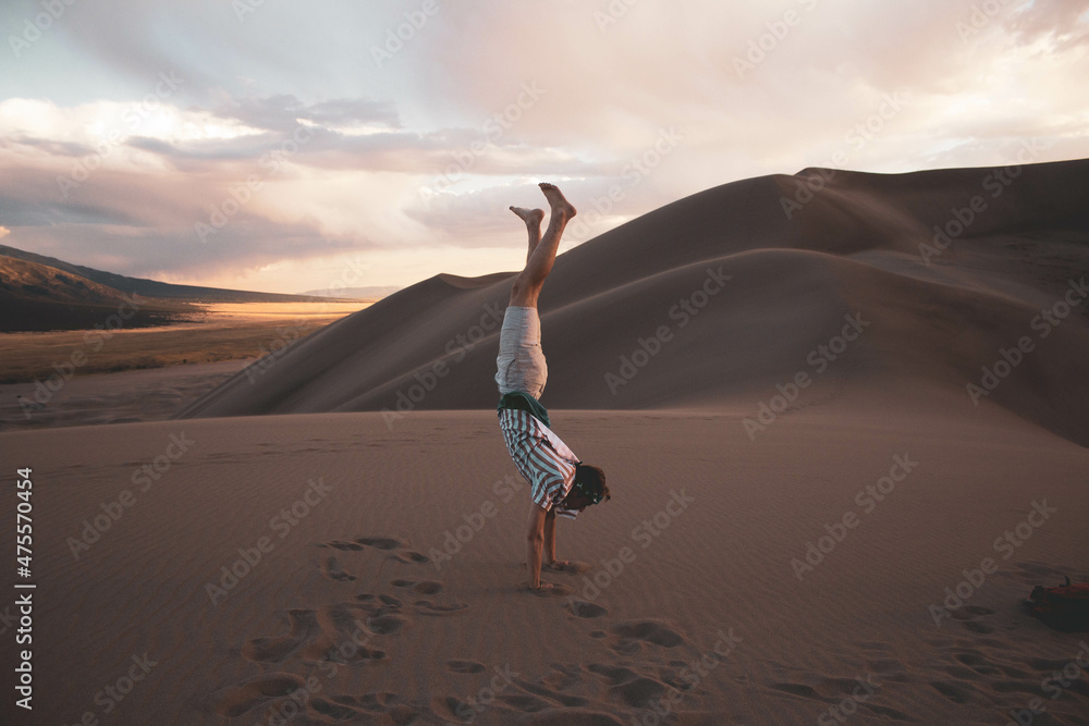 Man doing a handstand on a sand dune in the wild 
