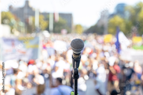 Protest or public demonstration, focus on microphone, blurred crowd of people in the background © wellphoto