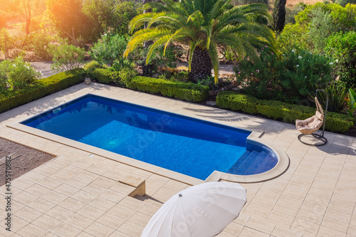 A modern pool in the garden with palm trees for relaxation of tourists near the hotel. Top view  summer  rocking chair.