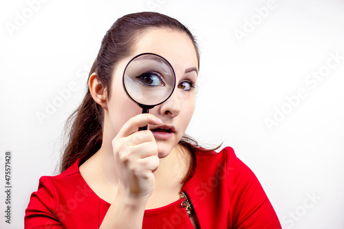 Young attractive woman with magnifying glass in her hand near the eye. Inspection, discovery, research, surprise, curiosity concept.