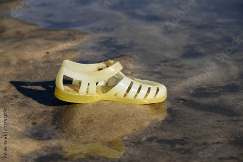 Une sandale d'enfant oubliée au bord de l'eau