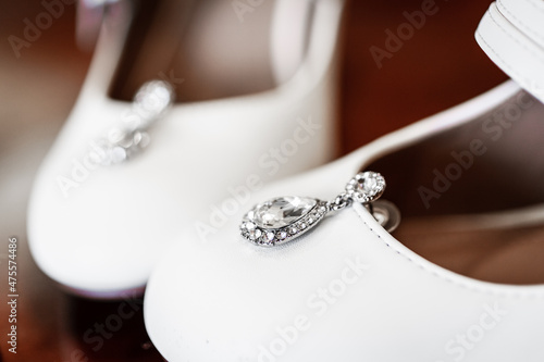 Bride's earrings sitting on top of her wedding day shoes. Detail shot with shallow depth of field.