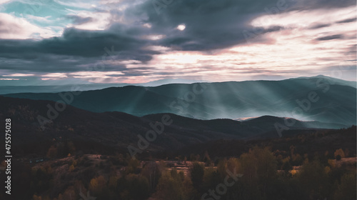 Mountain view with mist dense fog over autumn trees. Stunning view with sky, shining sun through white clouds. High quality photo