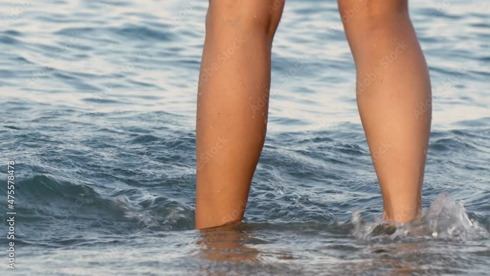 Female legs close up splashing in the sea's waves in the beach Female legs close up splashing in the sea's waves in the beach