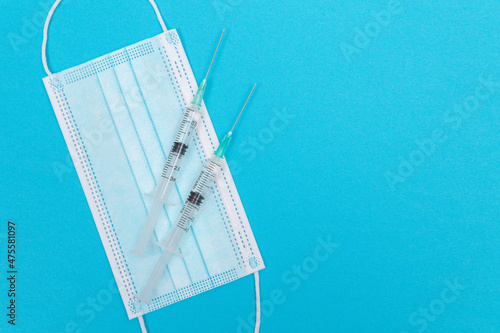 Several Syringe and Face Mask on Blue Table - Top View. Syringes are Prepared for Vaccination or Injection. Medical Experiment. Blue Disposable Medical Mask. Virus protection - Flat Lay