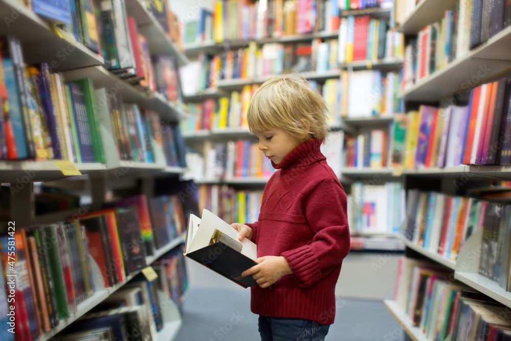 Cute blond toddler child, boy, reading book in a book store Cute blond toddler child, boy, reading book in a book store