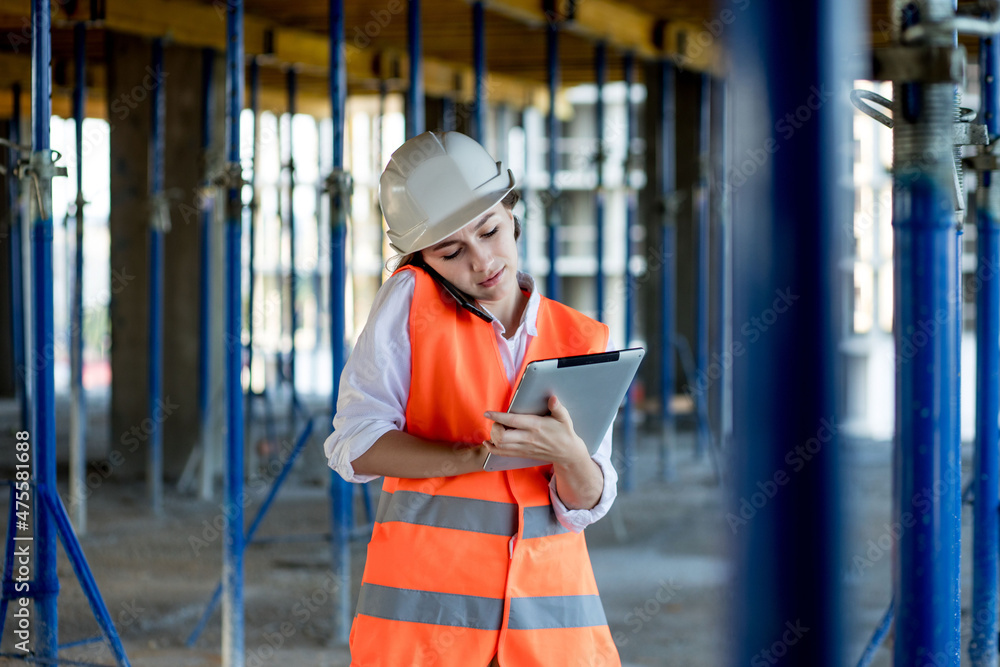 Construction concept of Engineer or Architect working at Construction Site. A woman with a tablet at a construction site. Bureau of Architecture Construction concept of Engineer or Architect working at Construction Site. A woman with a tablet at a construction site. Bureau of Architecture