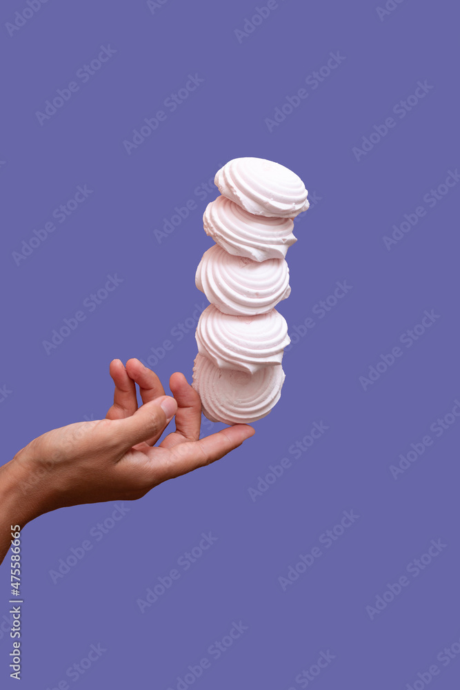 marshmallow floating in the air under hand against purple background
marshmallow floating in the air under hand against purple background