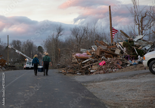 An Amish father and son off food and drinks as they walk through a tornado destroyed subdivision in Kentucky. photo