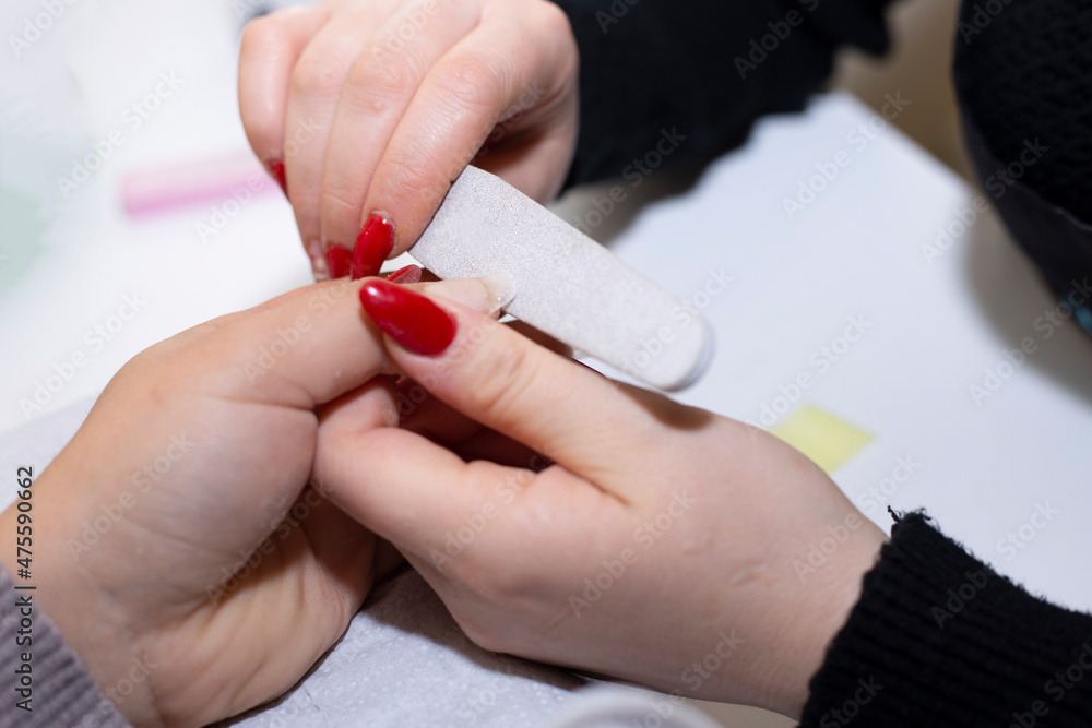 cropped image of nail technician filing nails to customer with nail file
