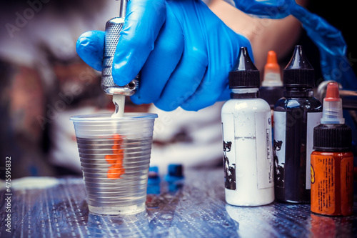 Hand of a master of the art of tattooing and a tattoo gun.