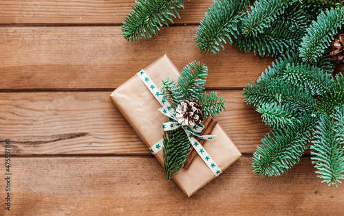 Christmas card template with fir tree branch and gift box on wooden background. Top view flat lay with copy space