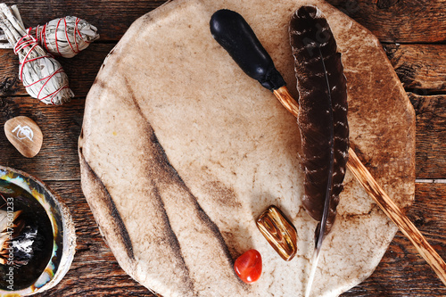 Photos A top view image of a handmade leather meditation drum with sacred feather and sage smudge sticks