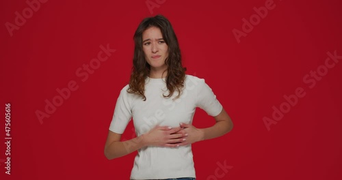 Sick young girl suffering from muscle pain in chest because of pinched nerve, intercostal neuralgia on red background 