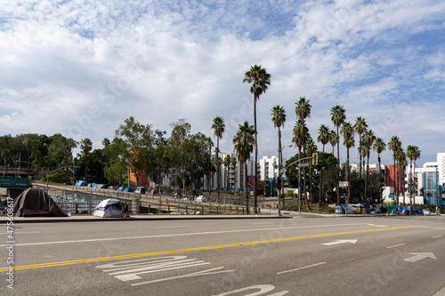 View of homeless tents lining to freeway in Los Angeles. Apartment buildings in the background