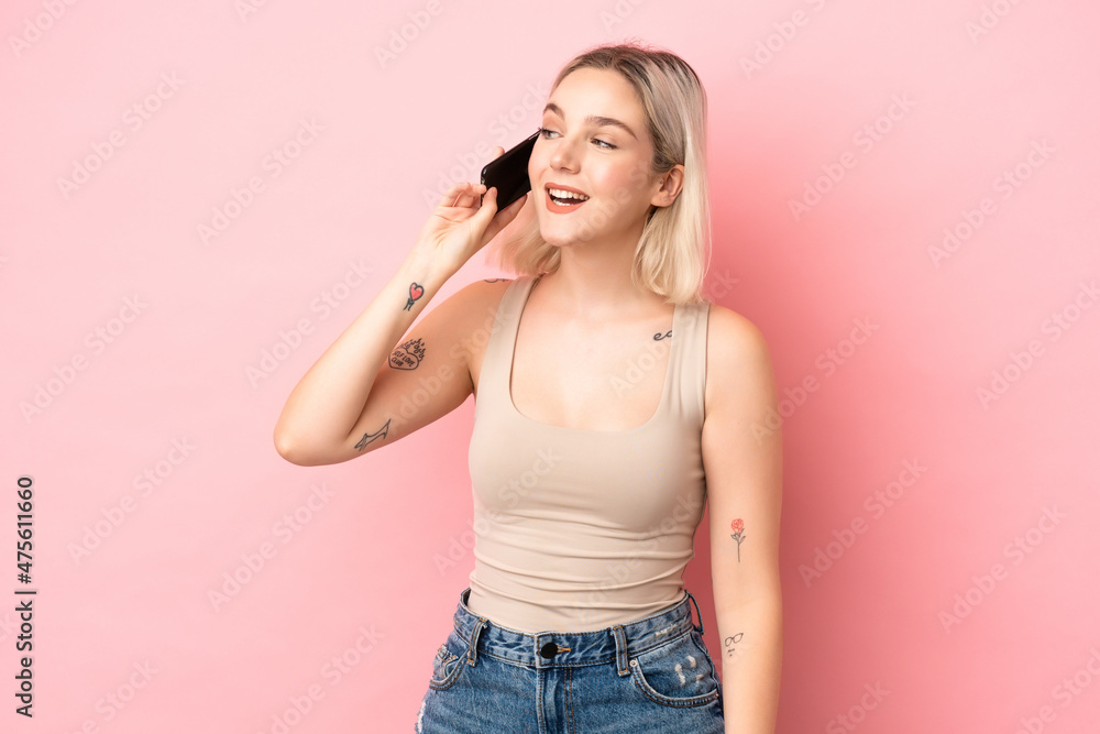 Young caucasian woman isolated on pink background keeping a conversation with the mobile phone Young caucasian woman isolated on pink background keeping a conversation with the mobile phone