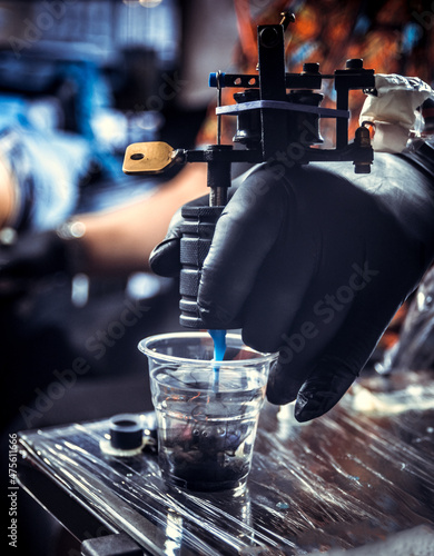 Hand of tattoo specialist with a tattoo gun.