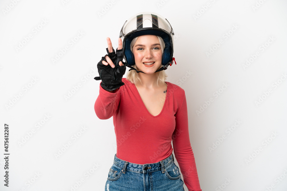 Young caucasian woman with a motorcycle helmet isolated on white background smiling and showing victory sign Young caucasian woman with a motorcycle helmet isolated on white background smiling and showing victory sign