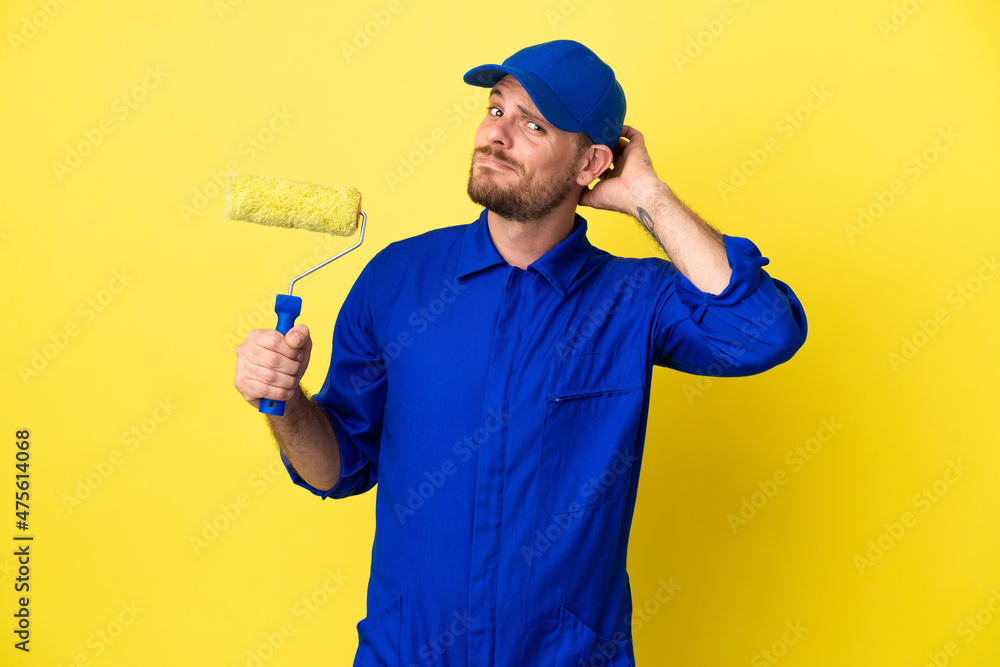 Painter Brazilian man isolated on yellow background having doubts Painter Brazilian man isolated on yellow background having doubts