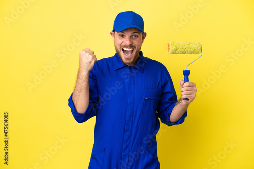 Painter Brazilian man isolated on yellow background celebrating a victory in winner position
