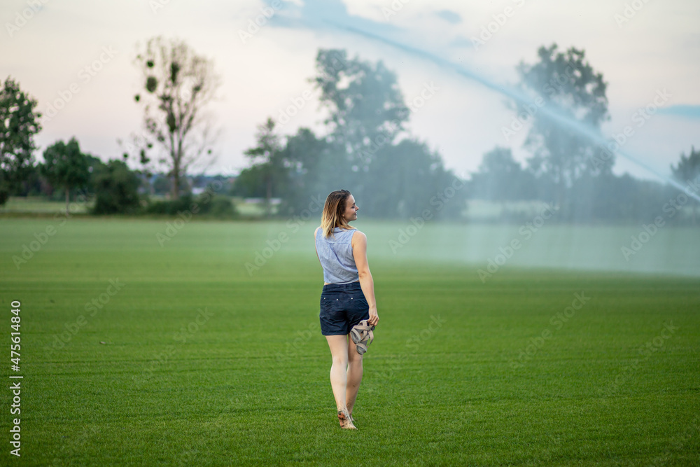 young woman having fun with water from a sprinkler.