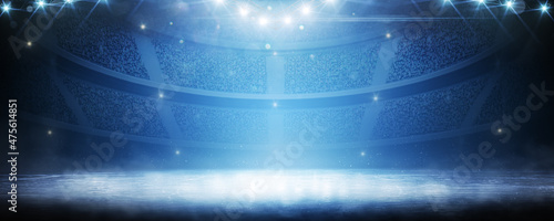 Sport background. Blue ice floor texture and mist. Snow and ice background. Empty ice rink illuminated by spotlights. Scene Illumination