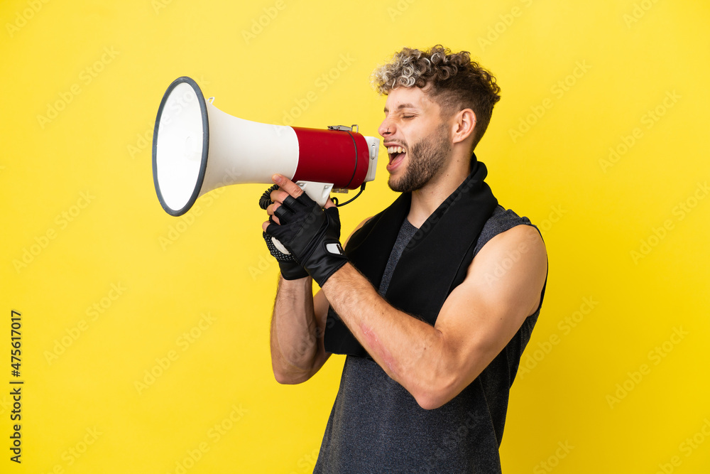 Sport caucasian man isolated on yellow background shouting through a megaphone Sport caucasian man isolated on yellow background shouting through a megaphone