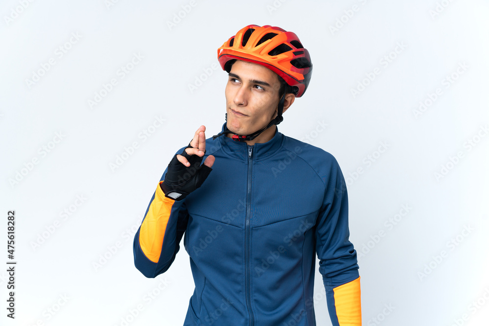 Young cyclist man isolated on background with fingers crossing and wishing the best Young cyclist man isolated on background with fingers crossing and wishing the best