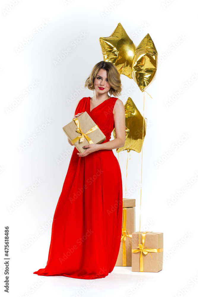 Party photo of elegance sexy lady in red dress with red lips and blond beautiful curly hair, smiling. Background of gold air balloons and gifts. Concept of the sale