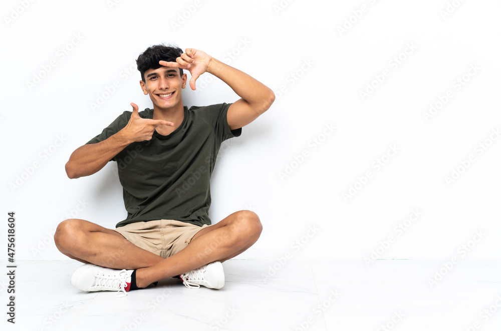 Young Argentinian man sitting on the floor focusing face. Framing symbol