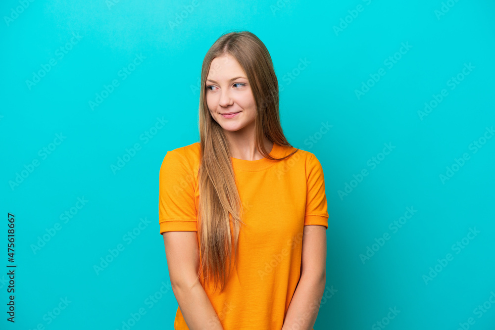 Young Russian woman isolated on blue background having doubts while looking side Young Russian woman isolated on blue background having doubts while looking side