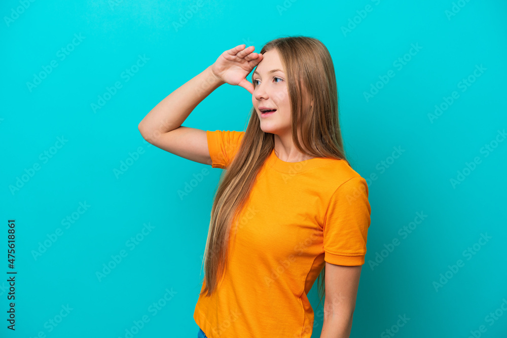 Young Russian woman isolated on blue background with surprise expression while looking side
