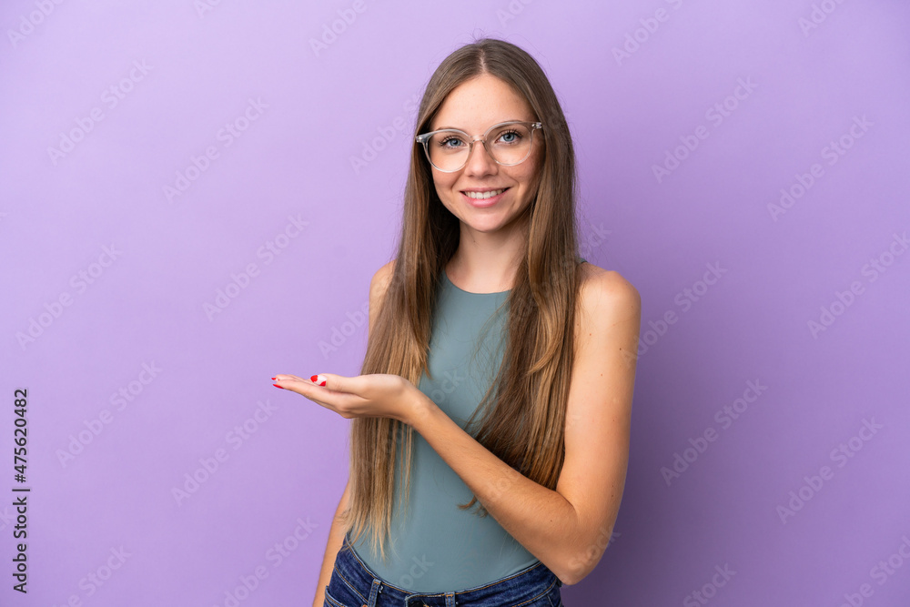 Young Lithuanian woman isolated on purple background presenting an idea while looking smiling towards Young Lithuanian woman isolated on purple background presenting an idea while looking smiling towards