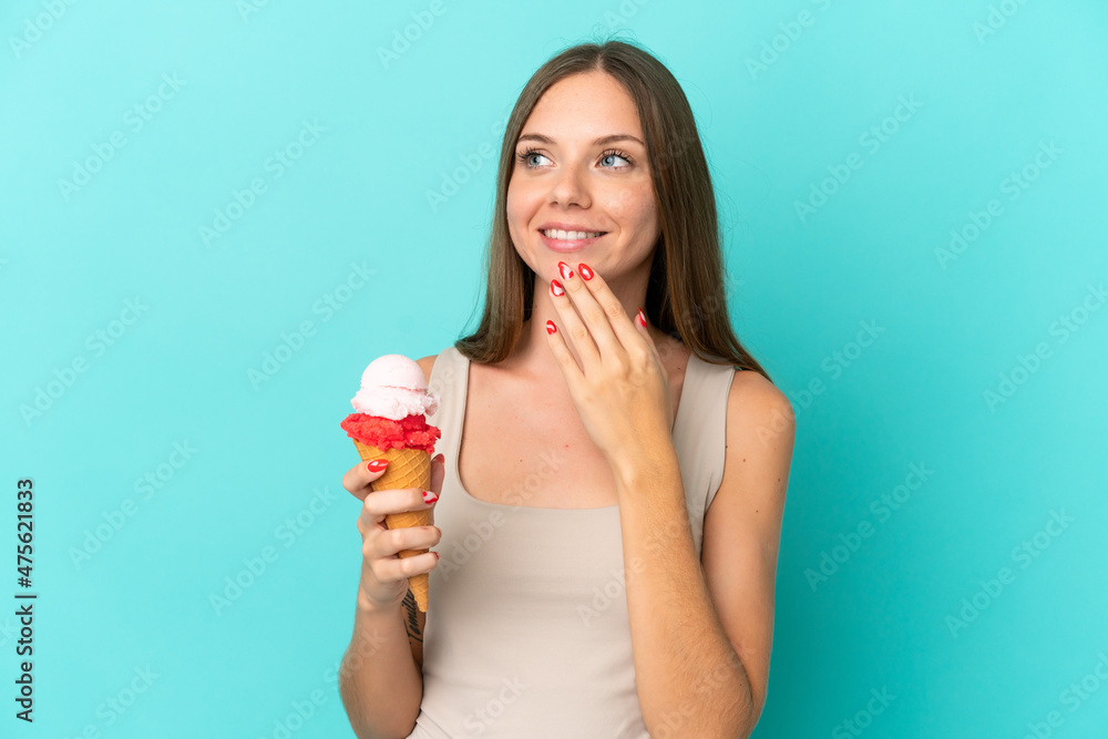 Young Lithuanian woman with cornet ice cream isolated on blue background looking up while smiling Young Lithuanian woman with cornet ice cream isolated on blue background looking up while smiling