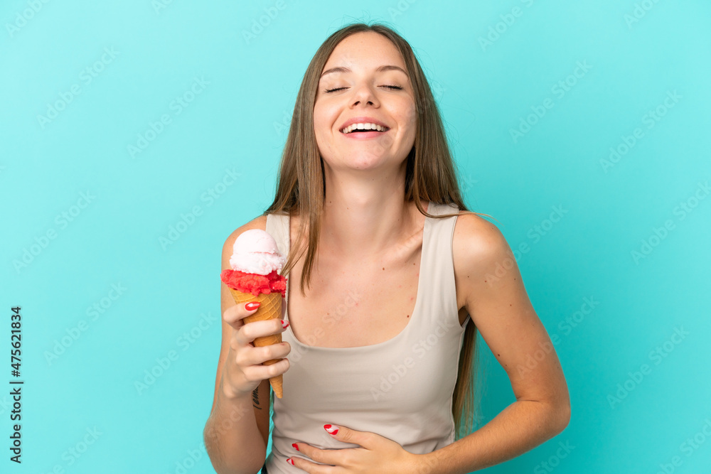 Young Lithuanian woman with cornet ice cream isolated on blue background smiling a lot Young Lithuanian woman with cornet ice cream isolated on blue background smiling a lot