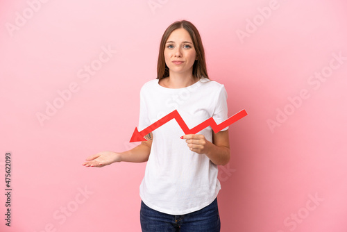 Slika na platnu Young Lithuanian woman isolated on pink background holding a downward arrow and