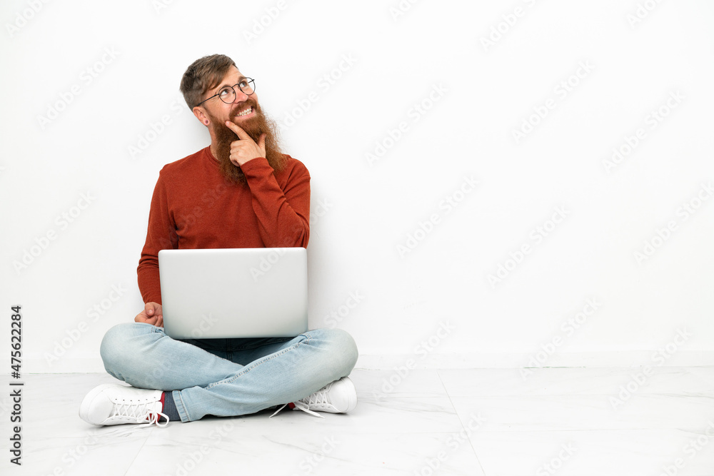 Young reddish caucasian man with laptop isolated on white background looking up while smiling Young reddish caucasian man with laptop isolated on white background looking up while smiling