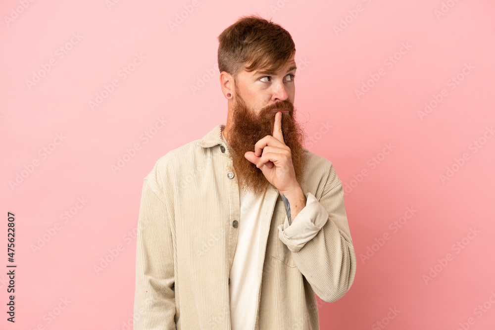 Young reddish caucasian man isolated on pink background showing a sign of silence gesture putting finger in mouth Young reddish caucasian man isolated on pink background showing a sign of silence gesture putting finger in mouth