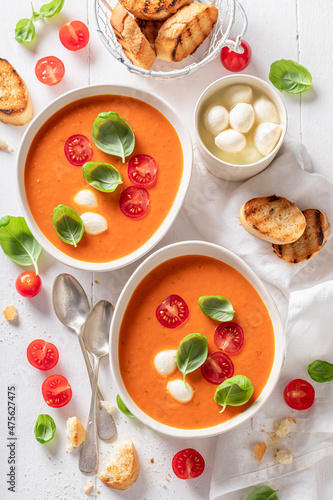 Red creamy tomato soup with mozzarella cheese and crostini.