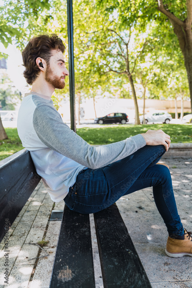 man listening to music sitting on a bench
