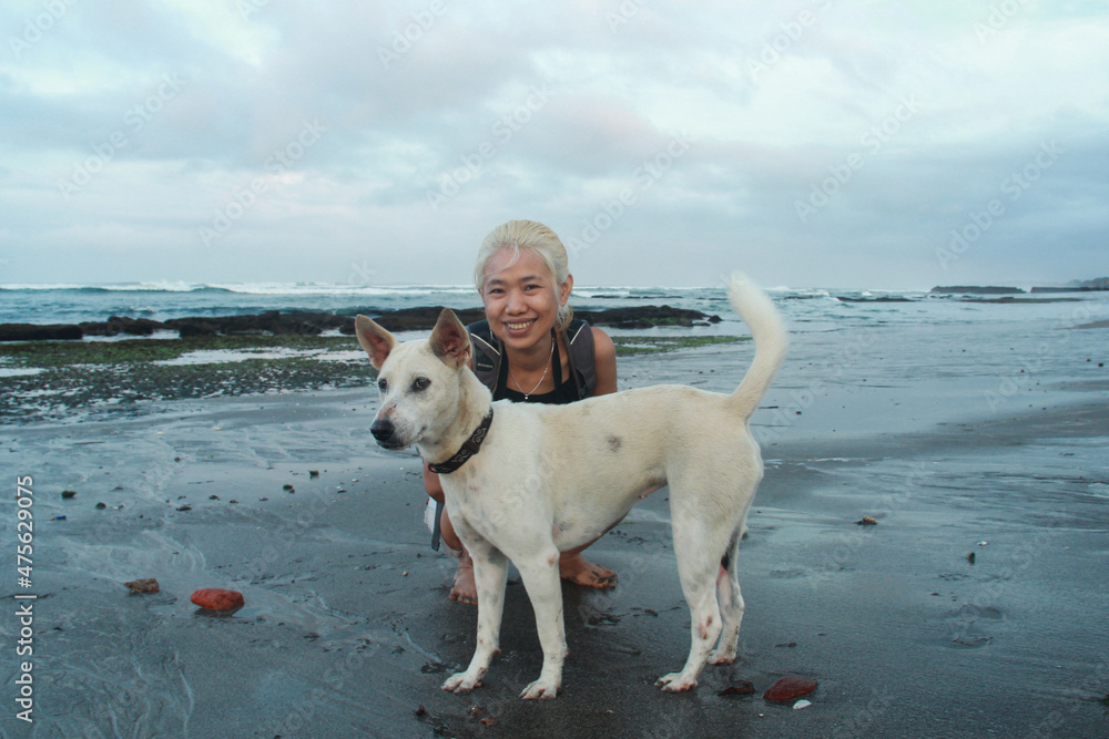 A woman walking and playing with the dog at Canggu beach in Bali, Indonesia.