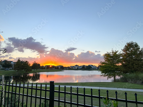 beautiful pink  orange and blue sunset reflecting on a lake in a suburban neighborhood.