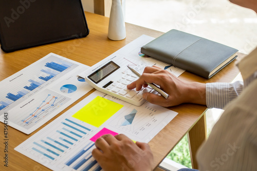 Young businessman presses last quarter earnings calculator to find solution of next quarter business finance, business people calculate numbers for workplace meeting, business people planning concept.